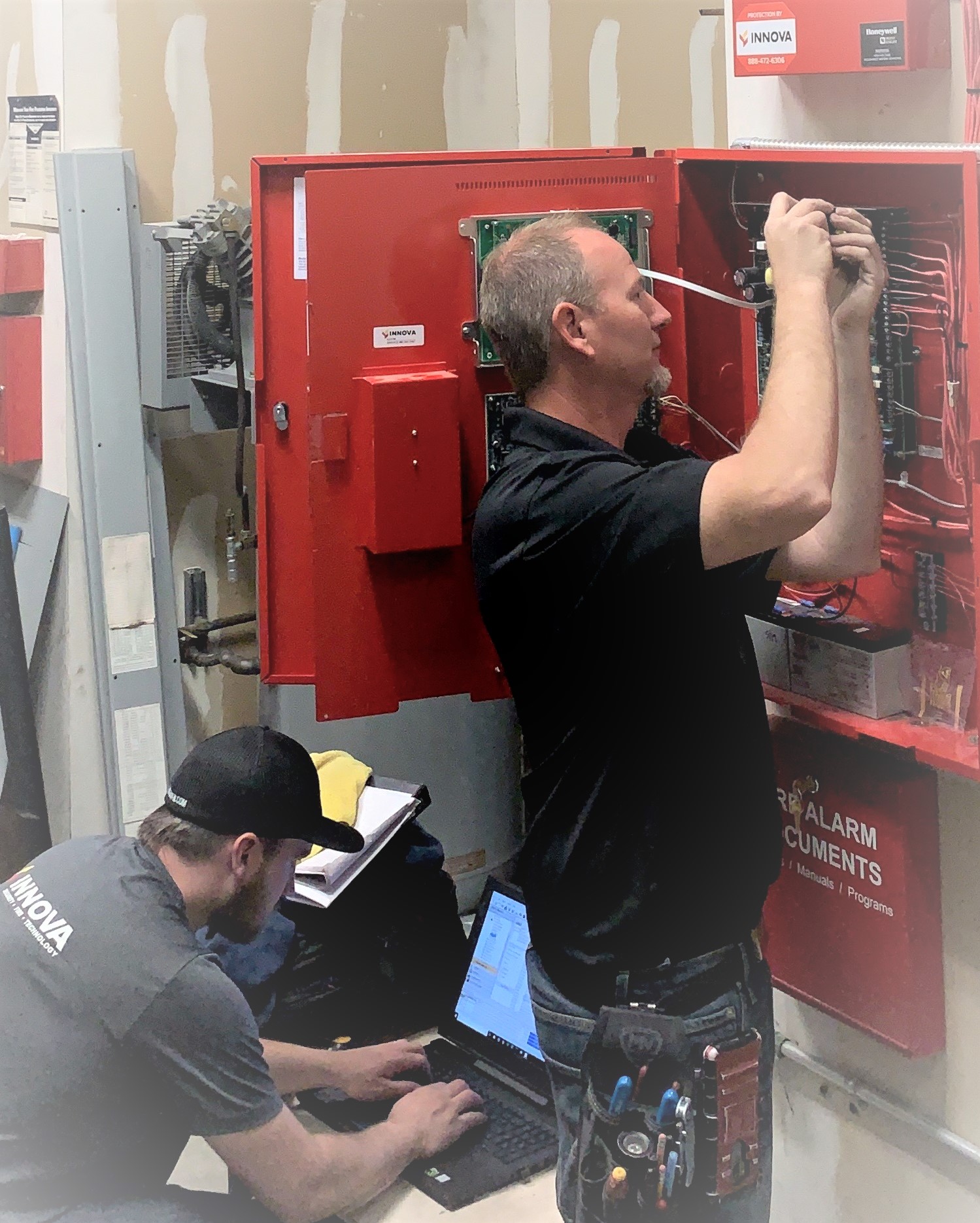 Innova NW technicians installing a commercial fire alarm panel.