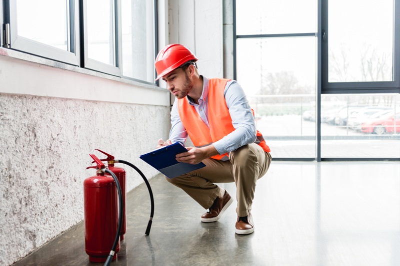 A man inspecting a fire extinguisher.